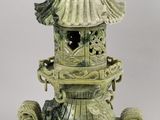 a green vase that has a bird on top of it