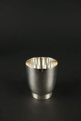 un gros plan d'une tasse argentée posée sur une surface noire
