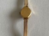 a gold watch on a white surface with a white background