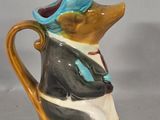 a small brown and black mouse with a blue hat on a brown and white pitcher
