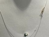une photo d'un collier orné d'une perle, porté par un mannequin
