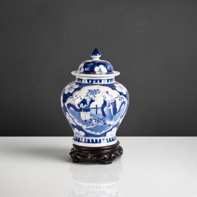 blue and white vase with a lid on a stand on a table
