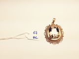 a close up of a gold pendant with a picture of a horse
