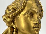 a gold statue of a woman with a bird on her head