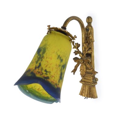 yellow and blue glass wall light with a gold bell on a white wall