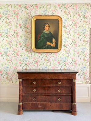 un tableau accroché au mur au-dessus d'une commode dans une pièce