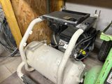 a small air compressor sitting on the floor in a garage