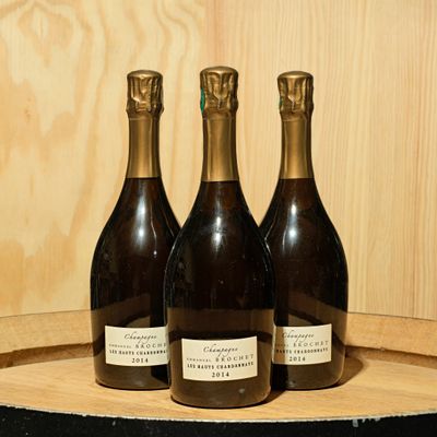 three bottles of wine sitting on top of a wooden barrel