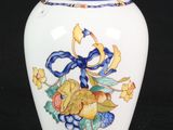 a white vase with a blue ribbon and flowers on it