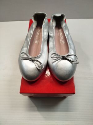 une paire de chaussons de danse argentés posés sur une boîte rouge, elle-même posée sur une surface blanche