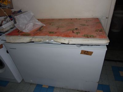 a mattress on top of a small refrigerator in a kitchen