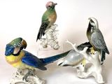 three figurines of birds sitting on a branch with a white background