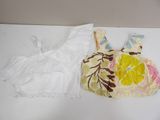 a white top and a yellow and pink dress on a table