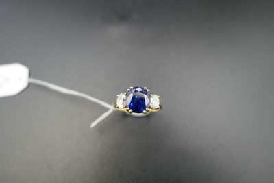 a close up of a blue sapphire and diamond ring on a black surface