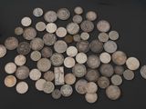 a pile of old silver coins on a black surface