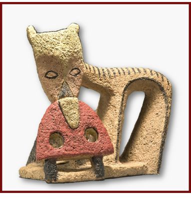 une sculpture représentant un chat tenant un champignon dans la gueule