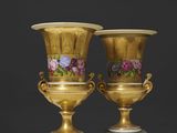 une paire de vases en or ornés de motifs floraux, posés sur un socle