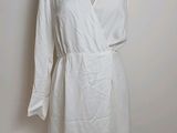 white dress on a mannequin stand against a white wall
