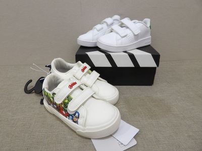 a pair of white shoes on the ground next to a box