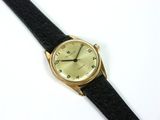 une photo d'une montre-bracelet en or montée sur un bracelet en cuir noir