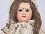 a close up of a doll wearing a white dress and bonnet