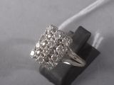 an image of a diamond clustered ring on a black piece of wood