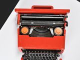 a red typewriter sitting on top of a white table
