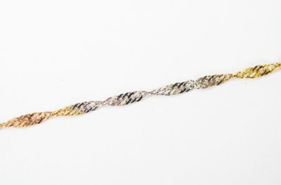 a close up of a gold and silver bracelet on a white surface