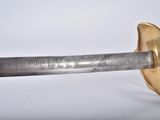 a close up of a sword with a gold handle on a white surface