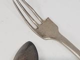 a fork, spoon and spoon rest on a table