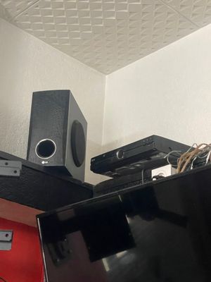 une photo d'une pièce avec une télévision, des haut-parleurs et un ordinateur portable