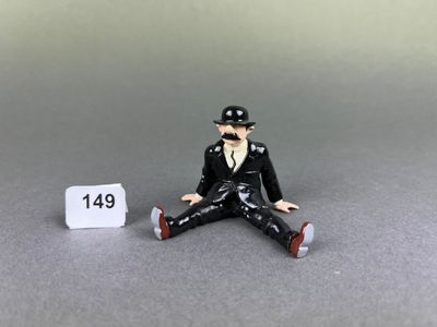 a figurine of a man sitting on the ground next to a sign