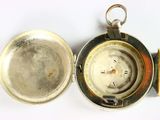 a silver pocket watch with a compass inside of it