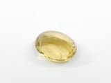 a close up of a yellow sapphire stone on a white surface