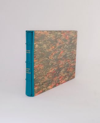 an old book with a blue cover sitting on top of a white surface