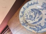 a blue and white plate with a bird on it sitting on a table