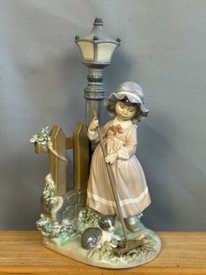 une figurine représentant une petite fille debout à côté d'un lampadaire