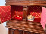 a small doll in a wooden cabinet with a red cover