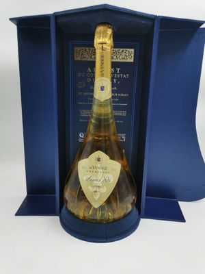 une bouteille de champagne dans un coffret cadeau bleu, posée sur une surface blanche