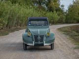 a green car that is driving down a dirt road