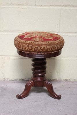 un petit tabouret en bois sur lequel est posé un coussin rouge et doré
