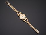 a lady ' s gold wrist watch with mother of pearl dial