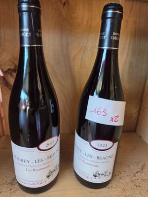 two bottles of wine sitting on a shelf next to each other