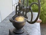 un petit moulin à café ancien posé sur une table en marbre