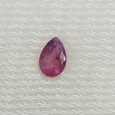 un gros plan d'une pierre rose en forme de larme posée sur un tissu blanc