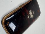 a small tortoise shell purse on a white surface