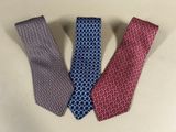 three different colored ties on a table with a white background