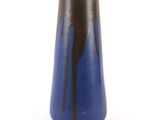un vase bleu présentant des stries noires sur un fond blanc