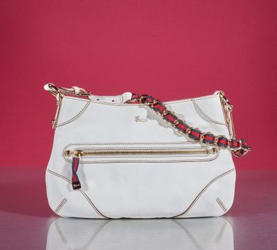 the white purse is sitting on a table with a red wall in the background