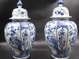 pair of blue and white vases with lids on a black surface